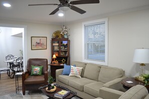 A living room with a sofa, armchair, coffee table, and a ceiling fan.