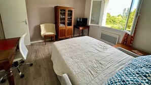 A hotel room with a bed, a desk, a chair, a TV, a cabinet, and a window with a view. - 3-room apartment in a residential complex. (11100 narbonne)