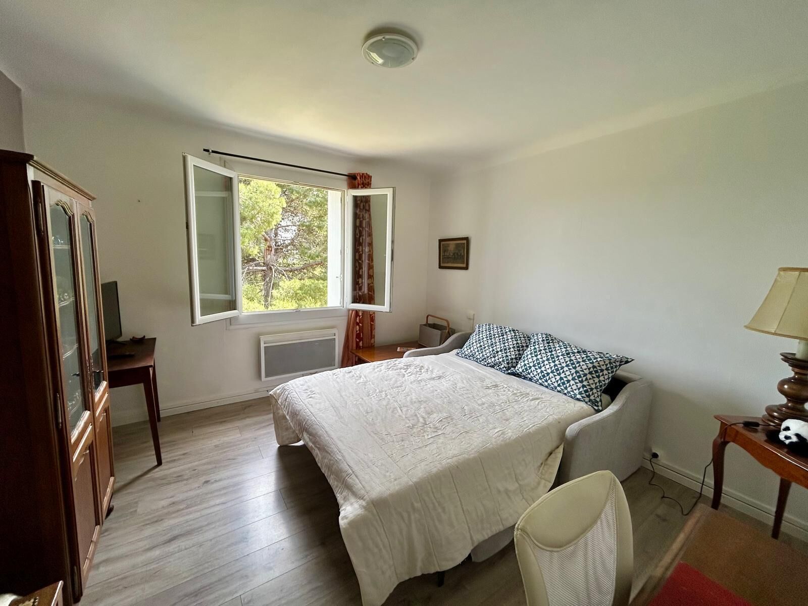 Een slaapkamer met een bed, een stoel, een bureau, een raam en een kast.