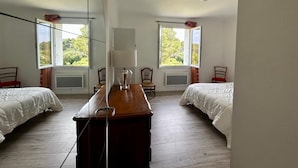 A room with two beds, a wooden table, and two windows with curtains. - 3-room apartment in a residential complex. (11100 narbonne)
