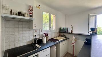 Una cocina moderna con gabinetes blancos, encimera negra, microondas y una ventana que proporciona luz natural.