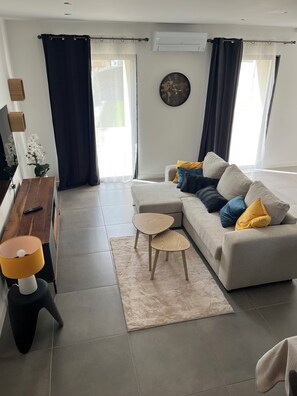 Un salon moderne avec un canapé, une table basse, un téléviseur et une horloge décorative accrochée au mur.