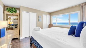 Una habitación de hotel con una cama, un tocador, un espejo, una ventana con vistas y una planta.