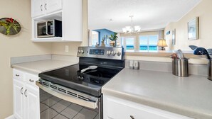 Una cocina con estufa, microondas y armarios.