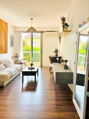 Ein modernes Wohnzimmer mit einer Couch, einem Couchtisch und einem Balkon mit Pflanzen.