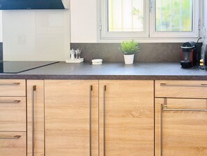 Eine Küche mit Holzausstattung, einer Arbeitsplatte, einem Fenster, einer Pflanze und Küchengeräten.