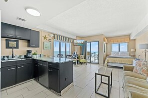 Ein modernes Hotelzimmer mit Küche, einem Balkon und einer schönen Aussicht sowie einer gemütlichen Sitzecke.