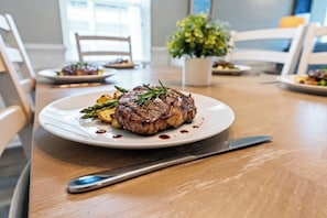 Ein Steak mit Spargel und Soße auf einem Teller, ein Messer und ein Tisch in einem Restaurant.