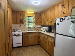 Una cocina con armarios de madera, una estufa blanca, un microondas y un refrigerador.