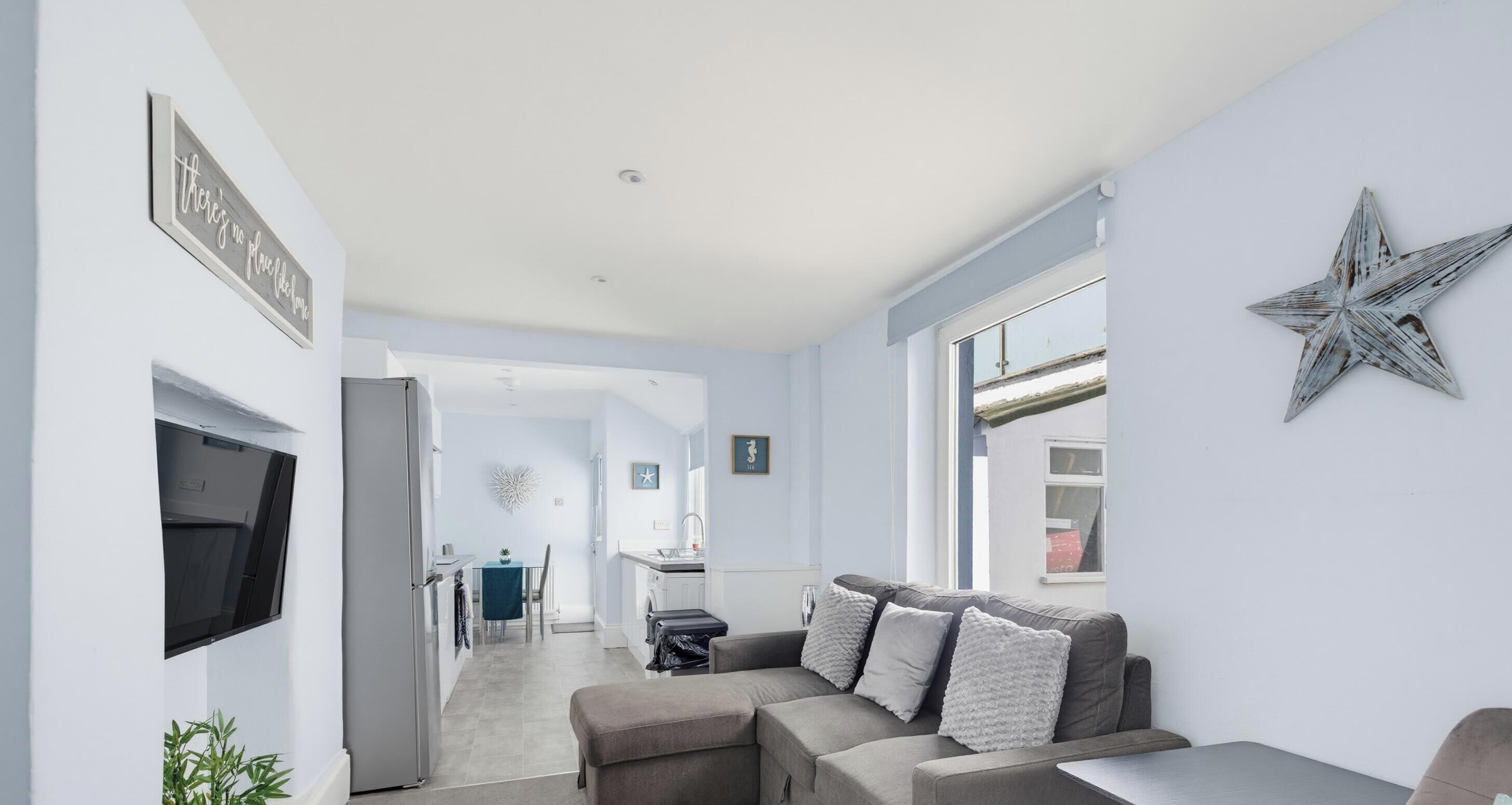 A modern living room with a grey sofa, a flat-screen TV, and a star decoration on the wall.