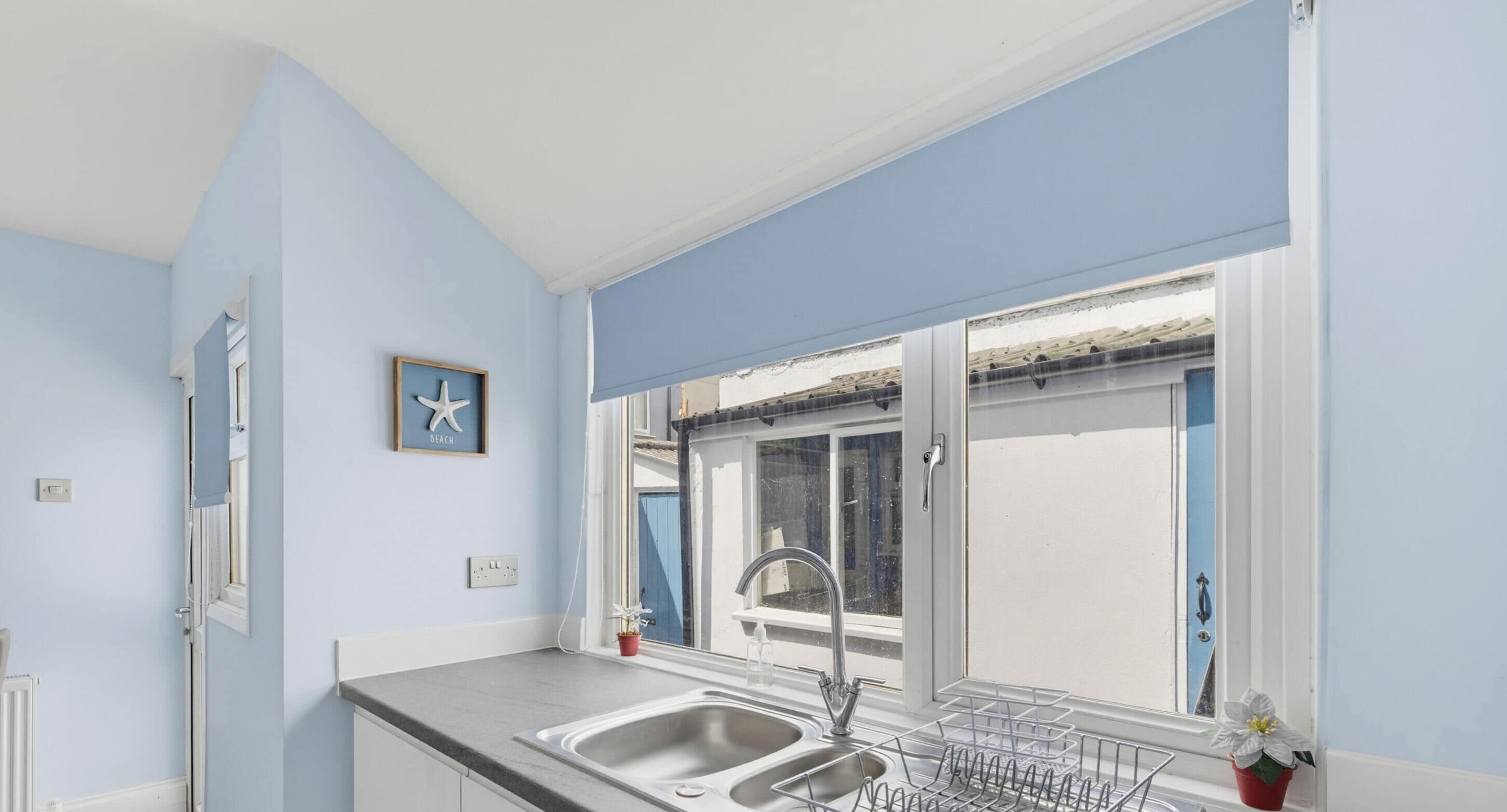 A kitchen with a double sink, a window with a view, and a framed picture on the wall.