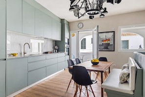 Eine moderne Küche mit hellblauen Schränken, einem Holztisch und einer Couch.