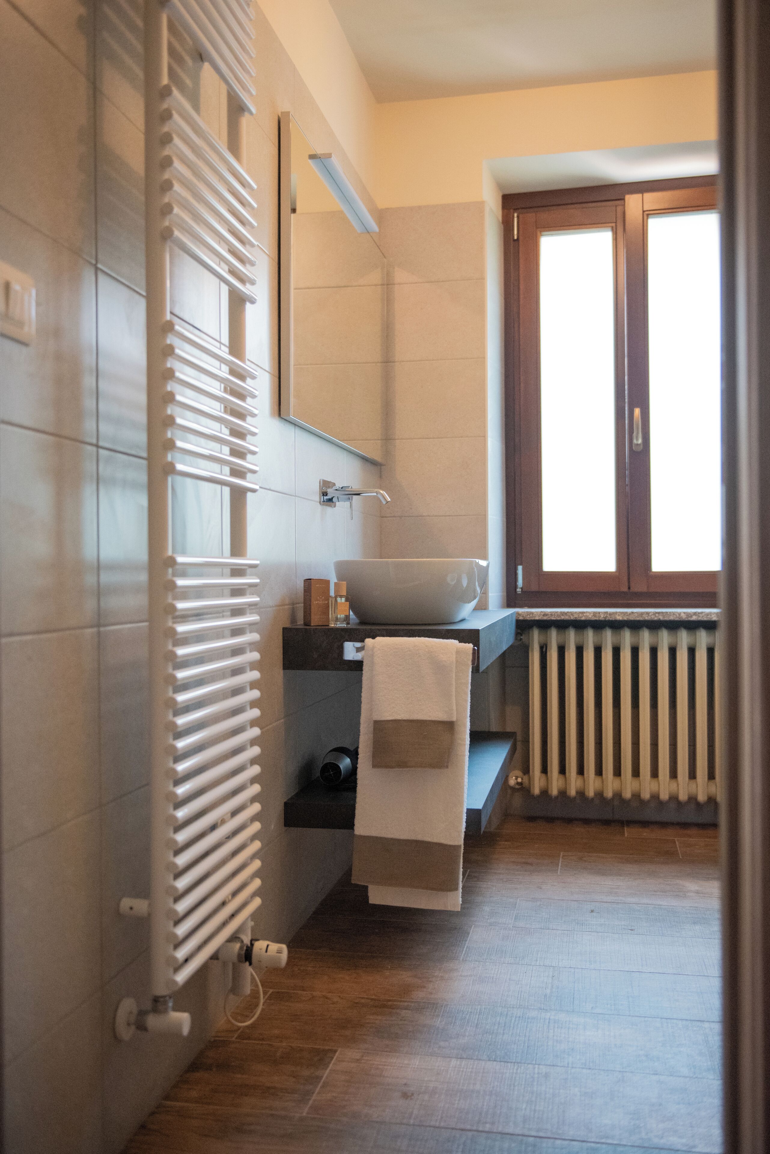 A bathroom with a white radiator, a sink, and a window with a view.