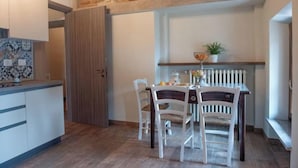 A dining area with a table and chairs, a radiator, and a potted plant. - ByVigin Camomilla – Space and Comfort for Families and Friends (Magliano Alfieri)