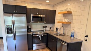 Een moderne keuken met roestvrijstalen apparatuur, een inbouwoven, magnetron en een spoelbak met een houten aanrechtblad.