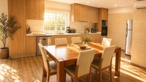 A modern kitchen with wooden cabinets, a dining table with chairs, a built-in oven, and a refrigerator. - Bed and breakfast with shared pool (10m2) (GODINHAÇOS)