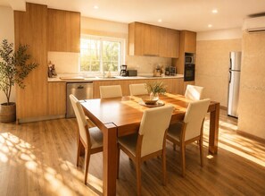 A modern kitchen with wooden cabinets, a dining table with chairs, a built-in oven, and a refrigerator. - Bed and breakfast with shared pool (10m2) (Braga)