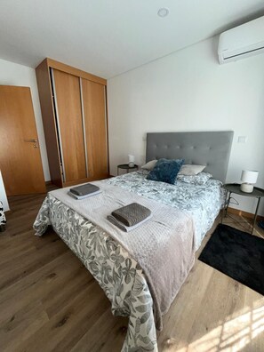 A bedroom with a bed, a wardrobe, a bedside table, and an air conditioning unit. - Bed and breakfast with shared pool (10m2) (Braga)