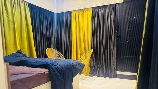 A bedroom with a bed, a chair, and curtains.