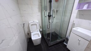 Une salle de bain comprenant des toilettes, un espace douche et un lavabo.