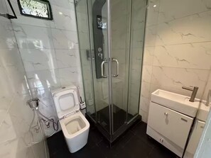Ein Badezimmer mit Duschkabine, Toilette und Waschbecken.
