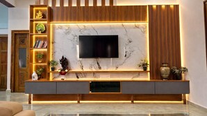 Un salon moderne avec un mur en marbre, un téléviseur à écran plat, des étagères en bois et une console.