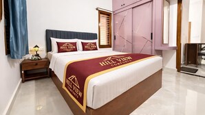 Une chambre d’hôtel avec un grand lit, une table de chevet, une armoire et une fenêtre avec des stores.