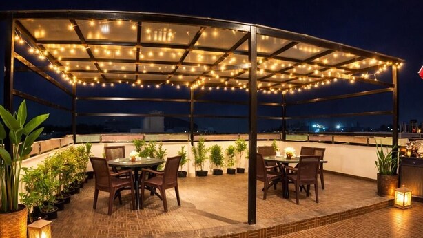Une terrasse extérieure avec des tables et des chaises, des guirlandes lumineuses et des plantes en pot.