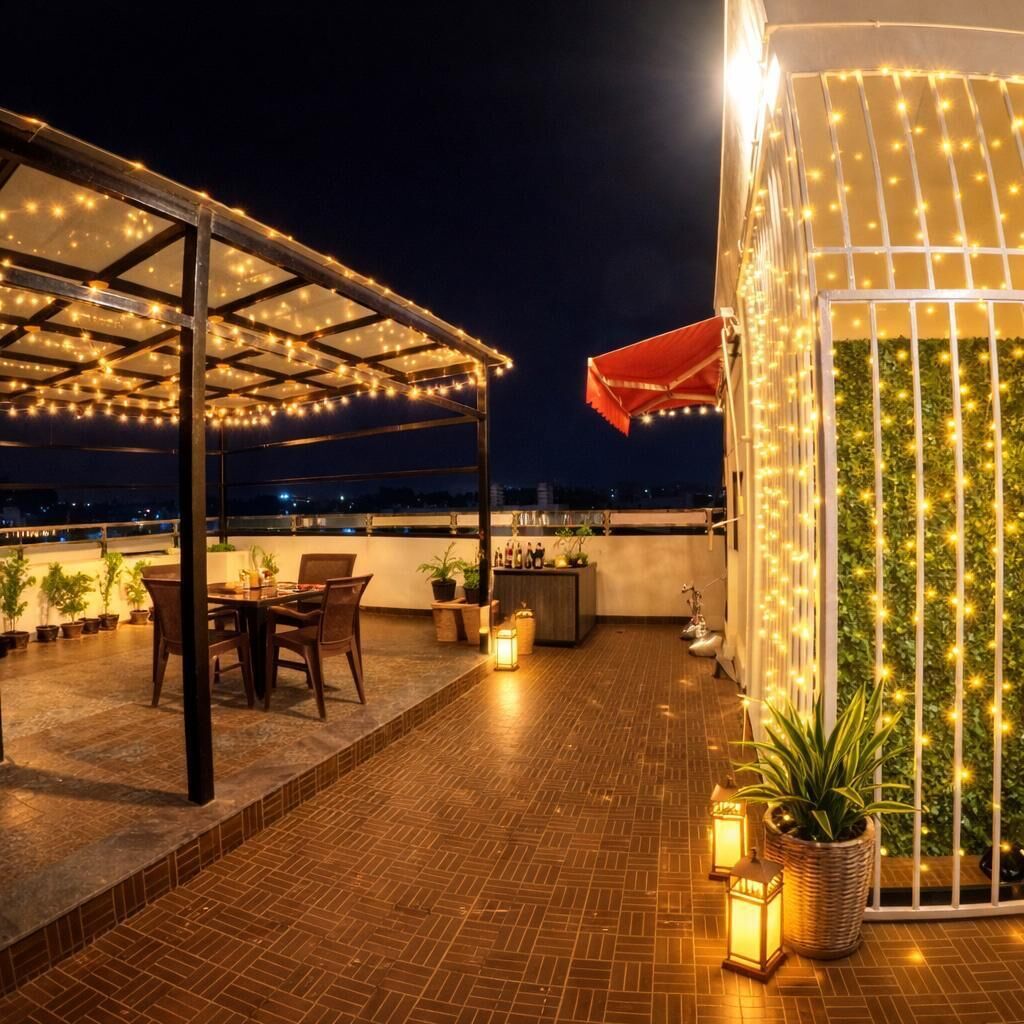A rooftop terrace with a covered seating area, potted plants, and string lights.