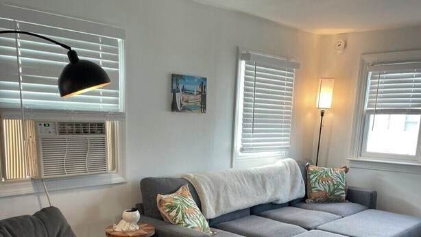 Ein modernes Wohnzimmer mit einem Ecksofa, einem kleinen Beistelltisch und einer Stehlampe.