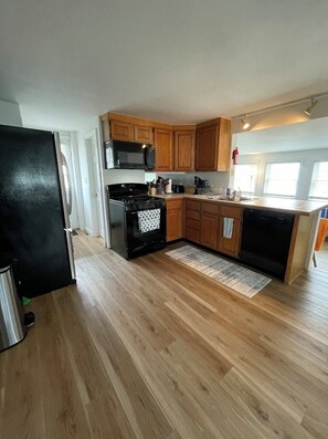 A kitchen with wooden cabinets, a black stove, and a microwave.