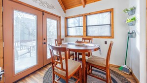 Zona pranzo con tavolo e sedie in legno, un elemento decorativo a parete e una finestra con persiane.