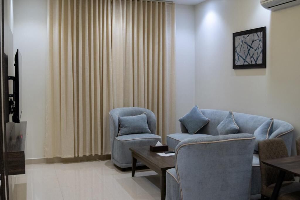 Una sala moderna con sofá, sillón y televisor.