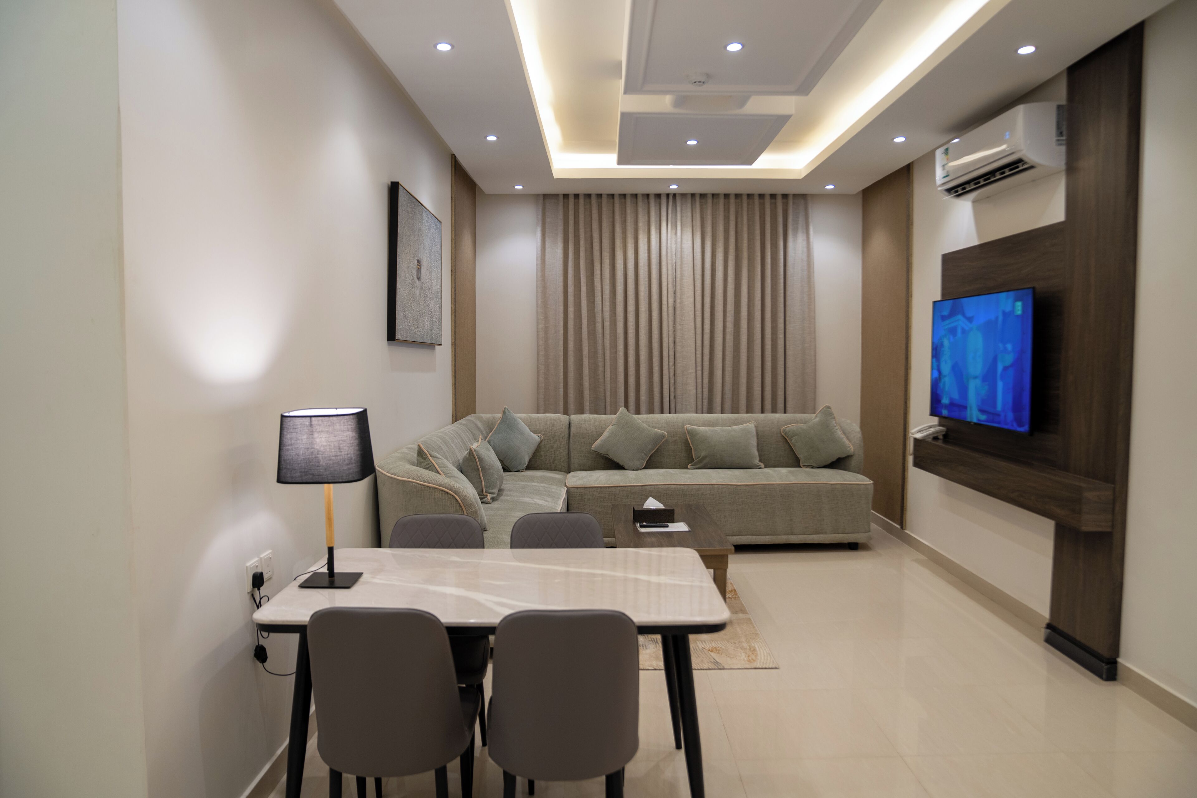 A modern living room with a sofa, TV, dining table, and chairs.