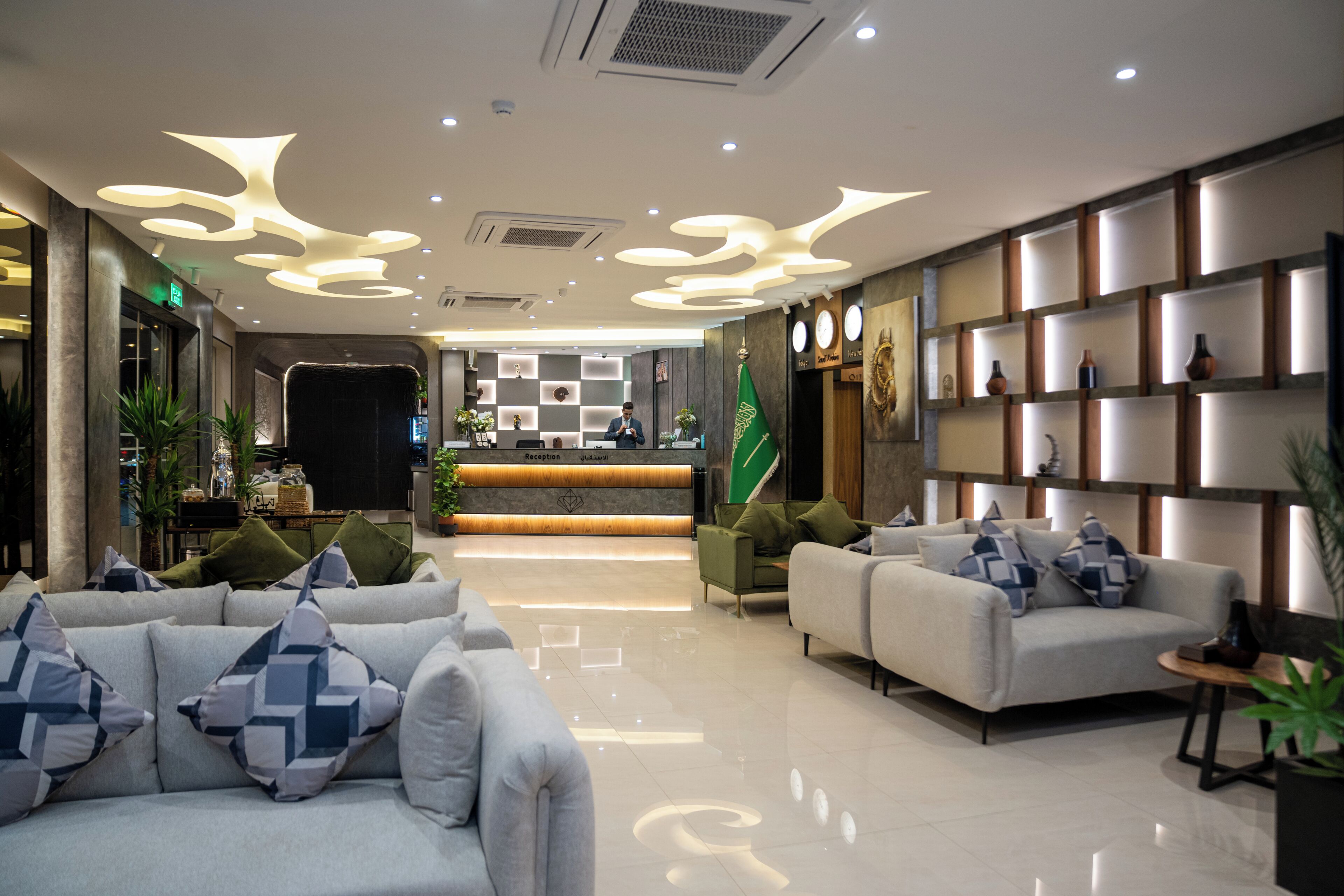 Un vestíbulo moderno con sofás, un mostrador de recepción e iluminación decorativa.