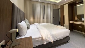 Ett modernt hotellrum med en stor säng, sängbord, en garderob och en spegel.