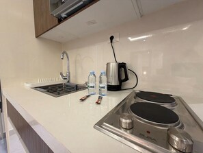 A kitchen with a sink, a kettle, and a stove. - 102 JRE Apartment With Stunning Boulevard Veiw (Amman)