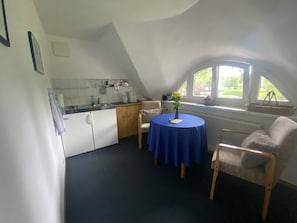 Une petite cuisine accueillante, avec un coin repas, une fenêtre donnant sur un beau paysage et une table agrémentée d’un vase de fleurs.