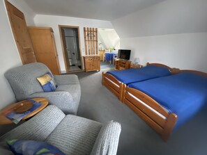 Une pièce comprenant un lit, un canapé, une commode en bois, un téléviseur et une petite table.