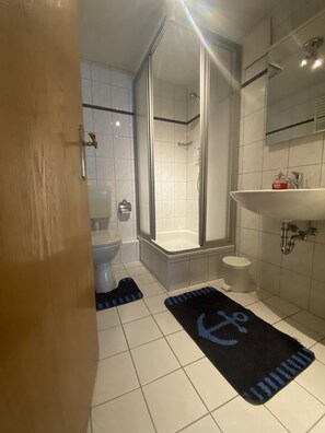 Een badkamer met een glazen douchecabine, toilet, wastafel en een bad.