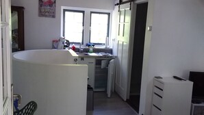 A compact kitchen with a central island, a dining area with a chair, and a television. - This studio is located 300m from the beach and the sea. (Petten)