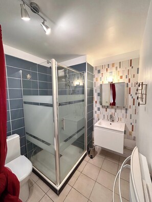 A modern bathroom with a glass-enclosed shower, a white sink, and a tiled floor. - Le millésime Vesle | Hypercentre | 6 couchages (Reims)