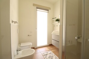A bathroom with a toilet, sink, and shower area.