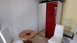 A small room with a bed, two white chairs, a wooden table, and a red wardrobe. - Bungalow in Saxon Switzerland (Sebnitz)