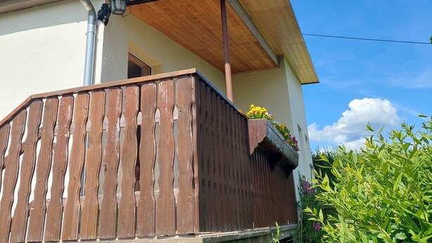 A house with a wooden balcony, a metal gutter, and a flower box. - Bungalow in Saxon Switzerland (Sebnitz)