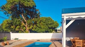 Ein Garten mit Holzterrasse, Schwimmbad und überdachter Terrasse.
