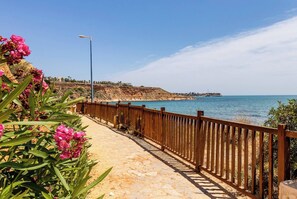 Ein Küstenweg mit Holzwand, der zu einer Klippe mit Blick aufs Meer führt.
