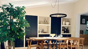 Ein stilvoller Essbereich mit Holztisch und -stühlen, einer Pendelleuchte und einem Blumentopf.