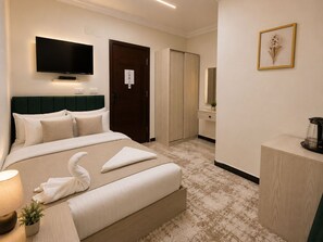 Ein Hotelzimmer mit Bett, Fernseher, Kleiderschrank, Spiegel und einer Kaffeemaschine.