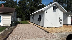 A single-story building with a gravel driveway, a garage, and a small attached shed. - River and Refuge Retreat!!!!Cozy 2-bedroom cottage in delightful Columbia NC (Columbia)